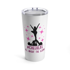 Könnte beinhalten: Ein weißer Edelstahlbecher mit einer rosa Silhouette von Cheerleadern in einer Pyramidenformation. Der Becher trägt den Text "#CHEERLIFE ALL ABOUT THE CLIMB".