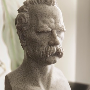 May include: A white marble bust sculpture of a man with a mustache and closed eyes.