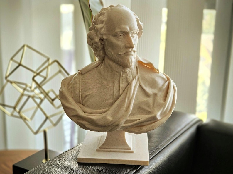 May include: A white bust sculpture of William Shakespeare, the famous playwright, poet, and actor. The bust is on a white pedestal and is made of a smooth, textured material.