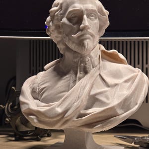 May include: A white 3D printed bust of William Shakespeare. The bust is on a white pedestal and has a detailed face and hair.