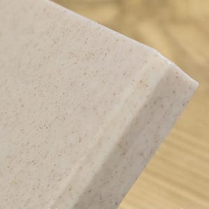 May include: Close-up of a marble composite material with a speckled pattern. The material is a light beige color with small, dark brown and black specks. The text "Marble Composite Material" is visible at the bottom of the image.
