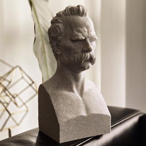 May include: A gray stone bust sculpture of a man with a mustache. The bust is detailed with realistic features and a textured surface.