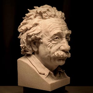 May include: A detailed bust of Albert Einstein, sculpted in a light beige material. The sculpture captures Einstein's iconic features, including his wild hair, mustache, and expressive face. The bust is set against a dark background.