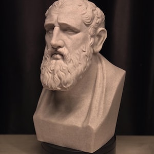 May include: A light beige bust of a man with a beard and curly hair. The sculpture has a stoic expression and is mounted on a black base. The bust is a classical art piece.