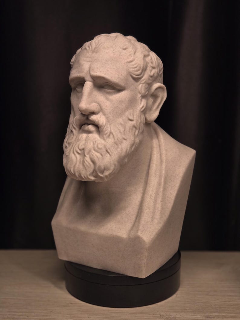 May include: A light beige bust of a man with a beard and curly hair. The sculpture has a stoic expression and is mounted on a black base. The bust is a classical art piece.