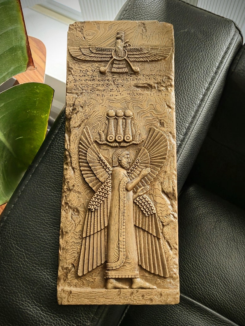 May include: A beige rectangular relief sculpture with detailed carvings of ancient figures and symbols. The artwork includes a winged figure, a bird with outstretched wings, and other intricate designs, suggesting a historical or mythological theme.