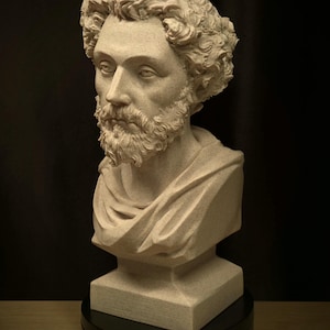 May include: A detailed bust sculpture of a man with curly hair and a beard. The sculpture is a light beige color and is set on a black rotating base. The man is wearing a draped garment.