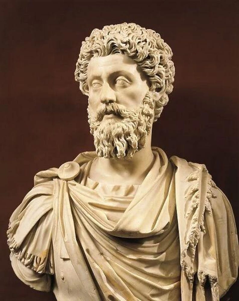 May include: A marble bust of a man with curly hair and a full beard. The sculpture features detailed facial features and is draped in classical robes. The bust is set against a dark brown background, highlighting the off-white color of the marble.