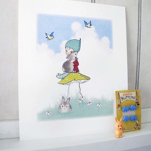 May include: A square art print featuring a character in a teal hat and red jacket sitting on a yellow-spotted mushroom, holding a grey rabbit. Two blue birds fly above, and a rabbit sits in the grass. Beside it is a pack of Kiddie's BUTTONS.