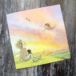 Puede incluir: Una ilustración de acuarela de un hada con alas volando en un cielo de puesta de sol. Una pequeña persona con un gato negro se sienta en una colina cubierta de hierba mirando hacia arriba al hada.
