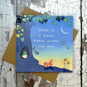 Puede incluir: Una tarjeta azul y amarilla con una cita que dice "Hay un mundo oculto dentro de nosotros." La tarjeta presenta una ilustración de dibujos animados de un pequeño duende verde asomándose desde un tronco de árbol y una ardilla roja sosteniendo una nuez.