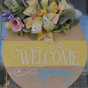 Corona primaveral artesanal en tonos pastel con letrero de bienvenida, pájaros y huevos: decoración encantadora para la puerta de entrada