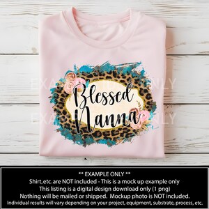 May include: A pink t-shirt with a design featuring a leopard print, turquoise paint splatter, and a gold oval with the text "Blessed Nanna" in a white font.