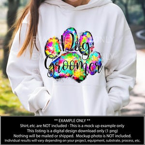 May include: A white hoodie with a colorful paw print design that says "Dog Groomer".