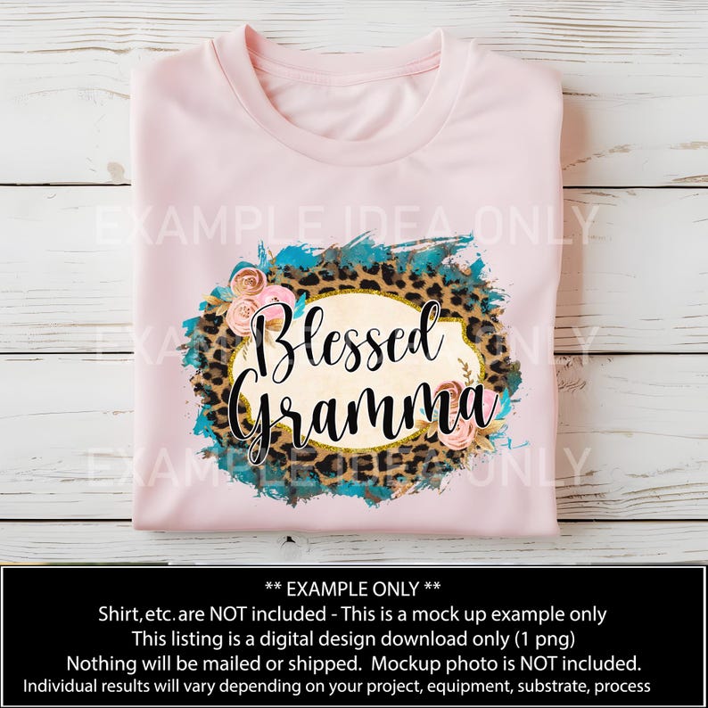 Puede incluir: Una camiseta rosa con un dise&ntilde;o que presenta un fondo de estampado de leopardo, salpicaduras de pintura azul turquesa y flores rosas. El dise&ntilde;o tambi&eacute;n incluye un &oacute;valo dorado con el texto "Blessed Gramma".