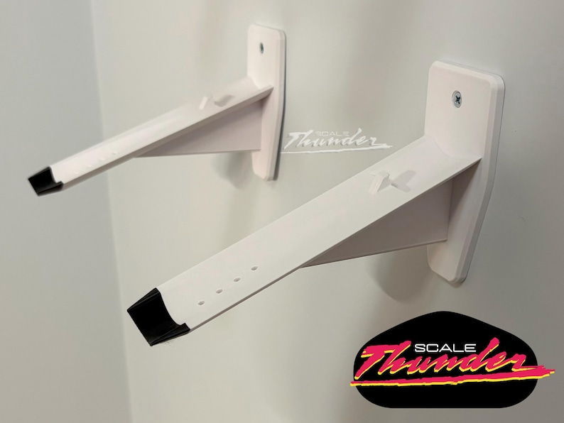 May include: Two white wall-mounted shelf brackets with black end caps. The brackets are angled and attached to the wall with screws. The logo "SCALE Thunder" is in the bottom right corner.