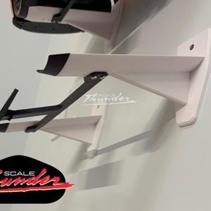 May include: White wall-mounted shelf with a black support bracket, designed to hold a model car. The shelf has a black accent on the front edge. The logo "SCALE Thunder" is visible.