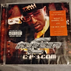 May include: CD case featuring a man wearing glasses and a black bandana with the text "TAU RECORDS." The album cover has the text "MURDER" and "C-P-3.COM." An orange sticker reads "FEATURING THE HIT SINGLES 'WHAT U GONNA DO' AND 'I'M NOT JUST.'" Parental advisory warning.