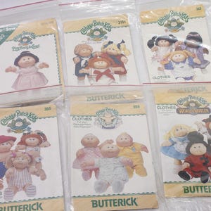 May include: A selection of Cabbage Patch Kids sewing pattern packets in plastic sleeves. The packets show illustrations of the dolls in different outfits. The brand name "Butterick" is visible on some packets.
