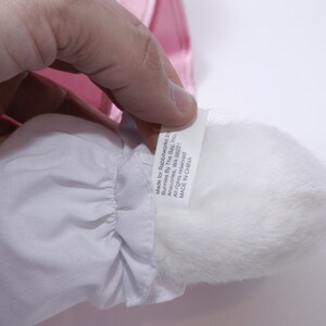 Peut inclure: Pompon en fourrure blanche avec une &eacute;tiquette blanche attach&eacute;e. L'&eacute;tiquette indique "Made for Rainbowworks Inc.  Bunnies By The Bay, Inc.  Anacortes, WA 98221  All rights reserved.  MADE IN CHINA."