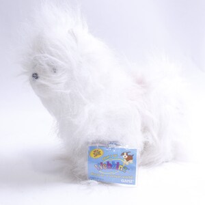 Puede incluir: Peluche de perro Webkinz blanco y esponjoso con una etiqueta azul y amarilla que dice "Webkinz, Descubre un mundo virtual, Ganz".