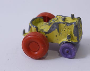Könnte beinhalten: Ein gelber Spielzeugtraktor mit roten und lila Rädern. Der Traktor hat eine graue Lackierung und ist aus Kunststoff.