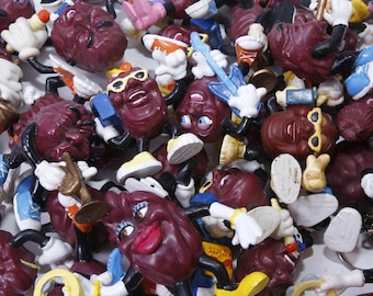 May include: A collection of colorful plastic figurines of grapes wearing sunglasses and playing musical instruments. The grapes are all different colors and have different expressions on their faces.