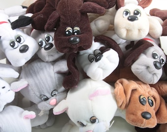 May include: A pile of plush puppy dog toys in various colors, including white, brown, and gray. The stuffed animals have large, expressive eyes and floppy ears. Some have spots or red collars.