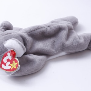 May include: Gray and white plush koala bear with a red Ty Beanie Baby tag. The tag has a white star and the text "Ty Beanie Baby".