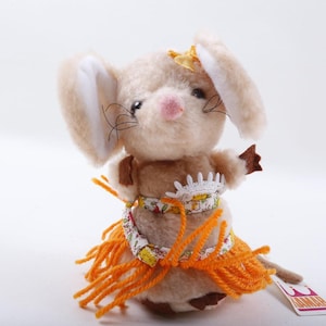 Könnte beinhalten: Eine Plüschmauspuppe mit großen Ohren, die einen Hula-Rock und ein florales Oberteil trägt. Die Maus hat eine rosa Nase, schwarze Schnurrhaare und einen gelben Stern auf dem Kopf. Der Rock ist aus orangefarbenem Garn.