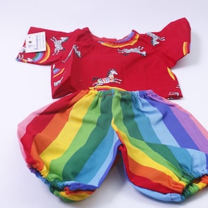 May include: A two-piece children's outfit featuring a red top with zebra and rainbow graphics, paired with rainbow-striped bloomers. The top has short sleeves and a round neckline. The bloomers are elasticated at the waist and legs.