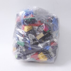 Puede incluir: Una bolsa de plástico llena de una variedad de ladrillos Lego de colores, incluyendo rojo, azul, amarillo, verde y negro.