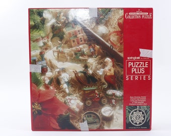 May include: A red box with a Christmas ornament collection puzzle on the front. The puzzle features a variety of ornaments, including a Santa Claus, a reindeer, a train, and a house. The box also includes the text "Keepsake Ornament Collection Puzzle" and "Puzzle Plus Series".