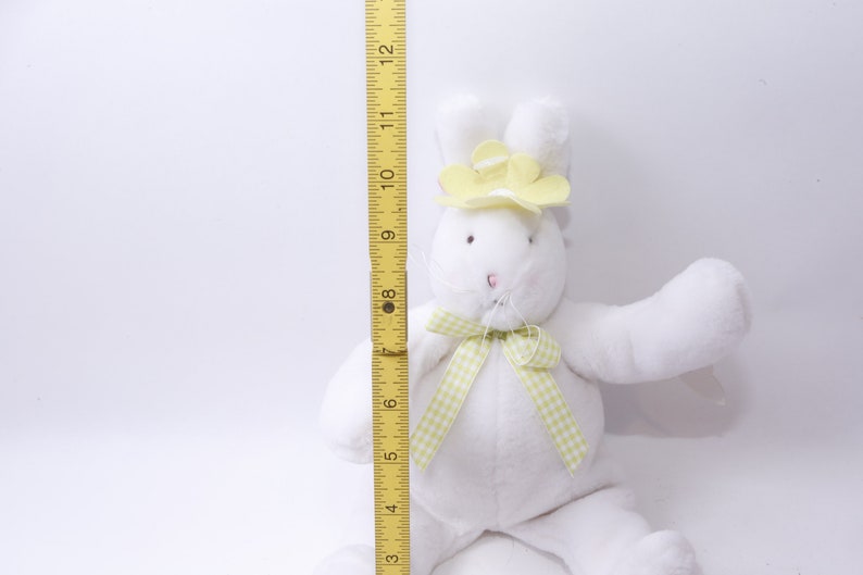 May include: White plush bunny rabbit wearing a yellow flower hat and a green and white gingham bow. The bunny is approximately 10 inches tall.