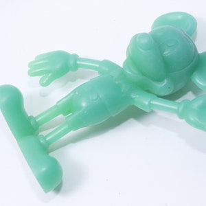 K&ouml;nnte beinhalten: Eine gr&uuml;ne Plastikfigur von Mickey Mouse. Die Figur steht mit ausgestreckten Armen.