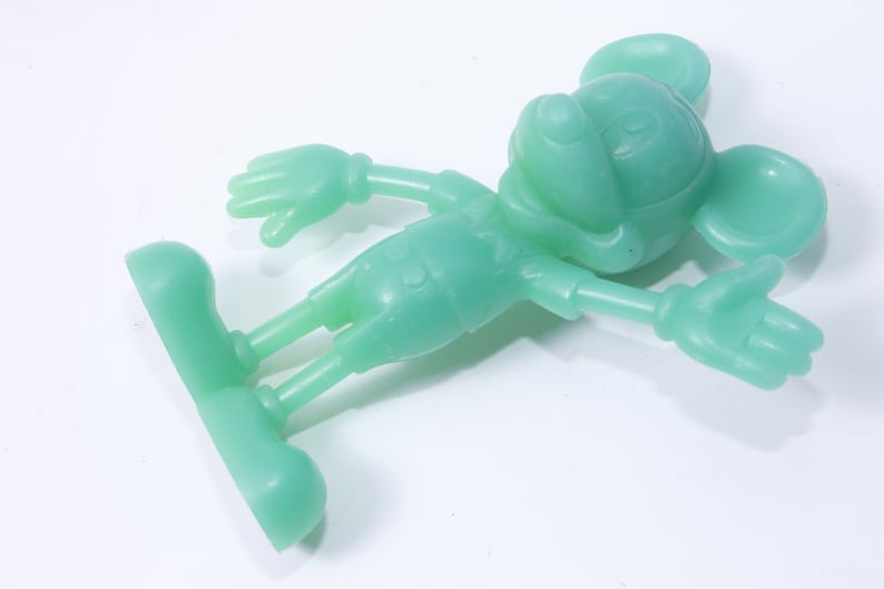 K&ouml;nnte beinhalten: Eine gr&uuml;ne Plastikfigur von Mickey Mouse. Die Figur steht mit ausgestreckten Armen.