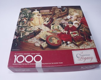 May include: A 1000 piece Springbok jigsaw puzzle box featuring a Christmas themed image of a room with a Christmas tree, toys, and a doll. The box is red with white text that reads "A Christmas Legacy" and "1000 pieces".