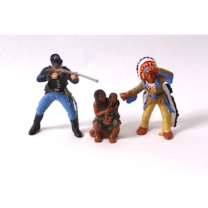 May include: A collection of miniature figurines depicting historical figures. The set includes a soldier in a blue uniform aiming a rifle, a Native American chief in a headdress, and a woman holding a child. The figurines are painted in various colors.
