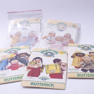 Könnte beinhalten: Fünf Vintage-Nähpakete für Cabbage Patch Kids. Die Packungen zeigen Illustrationen der Puppen in verschiedenen Outfits. Die Packungen sind mit "Butterick" beschriftet und enthalten die Wörter "Clothes" und "Cabbage Patch Kids".