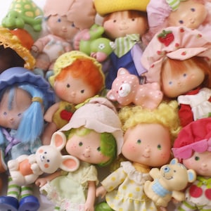 Peut inclure: Collection de poupées vintage Strawberry Shortcake. Les poupées ont différentes couleurs de cheveux, chapeaux et tenues. Certaines poupées tiennent de petites figurines d'animaux. Les poupées sont en bon état et semblent bien aimées.