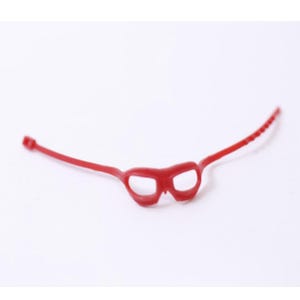 Puede incluir: Una pequeña máscara para los ojos de color rojo brillante con dos aberturas para los ojos y una correa fina. La correa se extiende desde la máscara y tiene una serie de pequeñas crestas. La máscara está hecha de un material flexible y está sobre un fondo blanco.