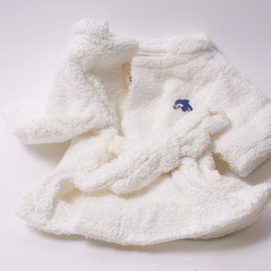 May include: A white terry cloth robe and matching belt, with a small blue embroidered dolphin logo on the chest. The robe is folded and laid out on a white surface.