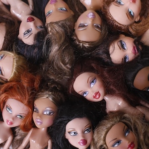 Könnte beinhalten: Eine Gruppe von Puppen mit langen, fließenden Haaren in verschiedenen Farben, darunter Blond, Braun und Schwarz. Die Puppen tragen verschiedene Outfits und haben unterschiedliche Gesichtsausdrücke.