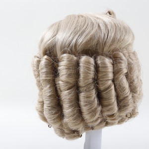Könnte beinhalten: Eine blonde Perücke mit einem großen, gekräuselten Dutt im Nacken. Die Perücke ist traditionell und formell gestylt.