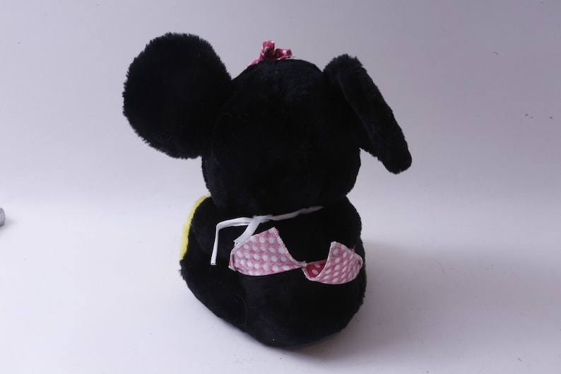 May include: Black plush toy mouse with pink polka dot fabric and a pink bow on its head. The mouse is sitting with its back to the camera.