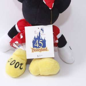 May include: Red and white polka dot dress with black sleeves and yellow shoes.  The plush toy is a Mickey Mouse character.  The tag reads "45 Years of Magic Disneyland $7.00".