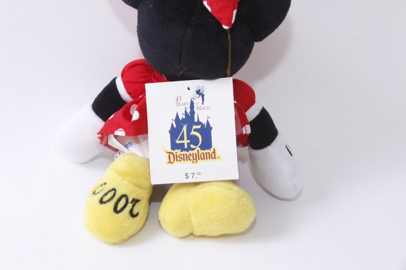 May include: Red and white polka dot dress with black sleeves and yellow shoes.  The plush toy is a Mickey Mouse character.  The tag reads "45 Years of Magic Disneyland $7.00".