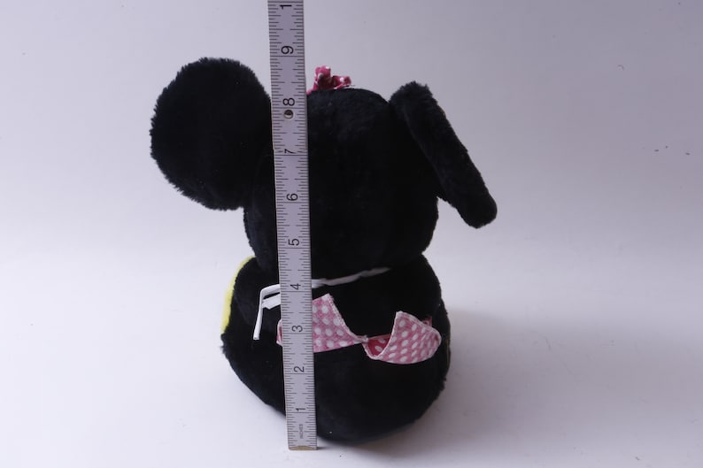 May include: Black plush toy with large ears, a pink bow, and a pink and white polka dot dress. The toy is approximately 6 inches tall.