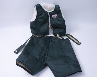 Op de afbeelding: Een groene gewatteerde vest en bijpassende shorts met een witte fleece voering. De vest heeft een ritssluiting en een klein patch met de tekst "Little Bear" op de voorkant.