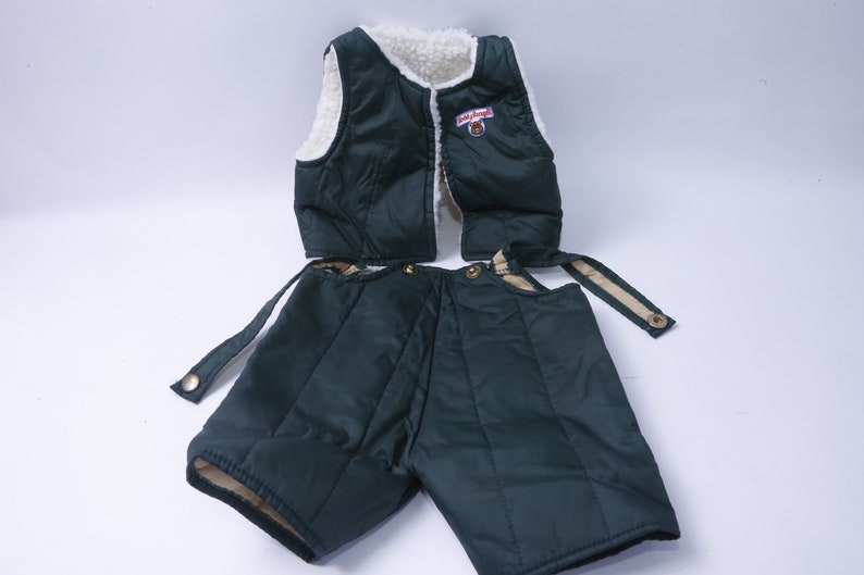 May include: A green quilted vest and matching shorts with a white fleece lining. The vest has a zipper closure and a small patch with the text "Little Bear" on the front.